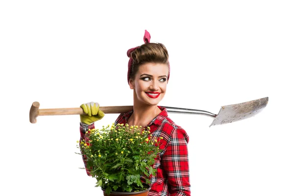 Woman with pin-up hairstyle holding yellow daisies and spade — 스톡 사진