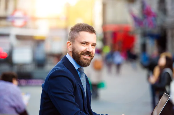 Hipster manager working on laptop on sunny Piccadilly Circus, Lo — Stockfoto