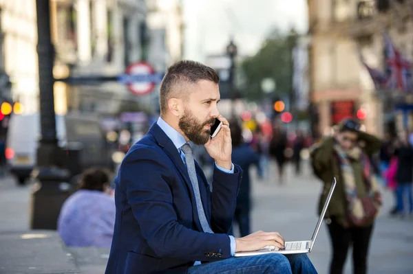 Gerente com laptop e telefone inteligente, ensolarado Piccadilly Circus, Lo — Fotografia de Stock