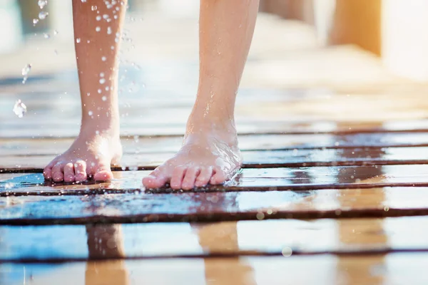 Detail of childs wet feet on pier, sunny summer day