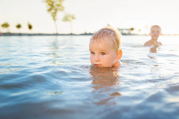 Kleine jongens zwemmen in het water op zonnige zomerdag — Stockfoto