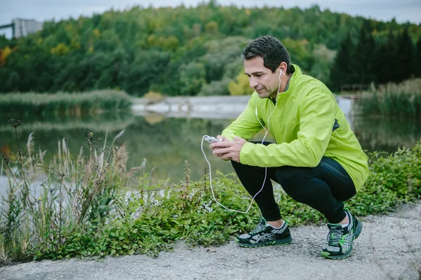 Löpare med smarta telefonen vilar — Stockfoto