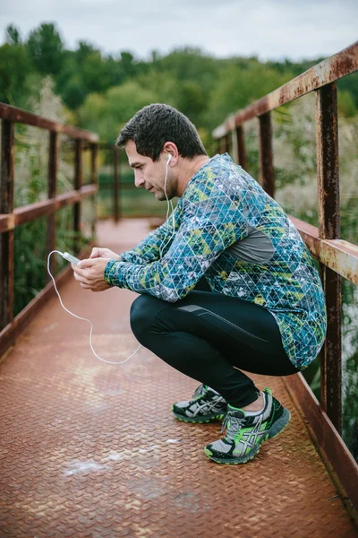 Runner with smartphone against green nature