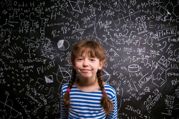 Ragazza con due trecce, grande lavagna con simboli matematici — Foto Stock