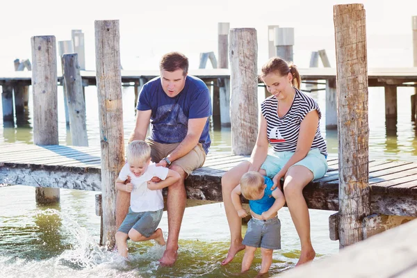 Family sitting on the pier, above water, sunny summer — Stock fotografie