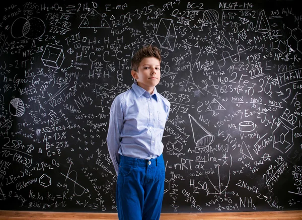 Niño contra pizarra grande con símbolos matemáticos y fórmula —  Fotos de Stock