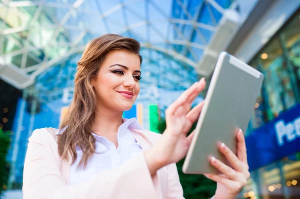 Geschäftsfrau arbeitet an Tablet gegen gläserne moderne Bürobui — Stockfoto