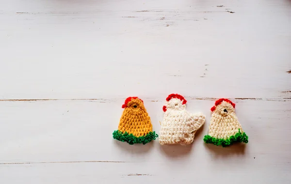 Three colorful crocheted Easter chickens against white wooden ba — 图库照片