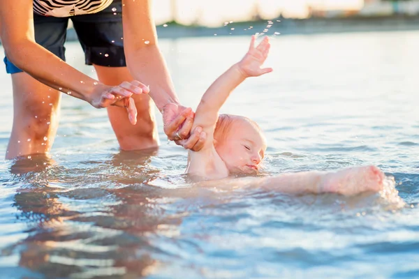 Pequeño niño deslizándose accidentalmente en el agua en poder de la madre —  Fotos de Stock