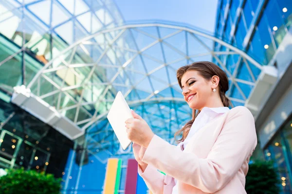 Businesswoman working on tablet against glassy modern office bui — Φωτογραφία Αρχείου