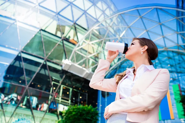 Donna d'affari che beve caffè dalla tazza termo contro ufficio bu — Foto Stock
