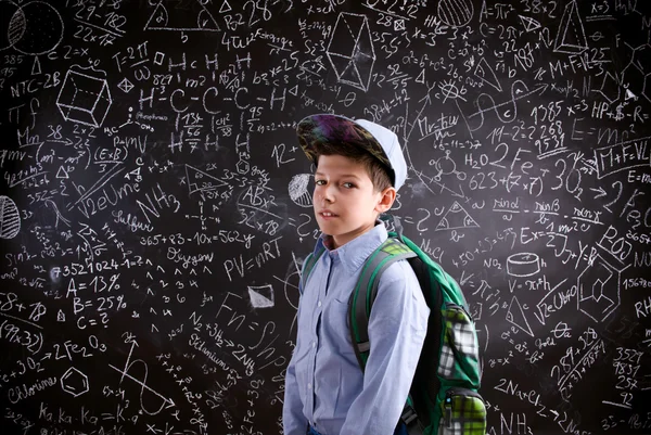Boy  with schoolbag against big blackboard with mathematical sym — Stok fotoğraf