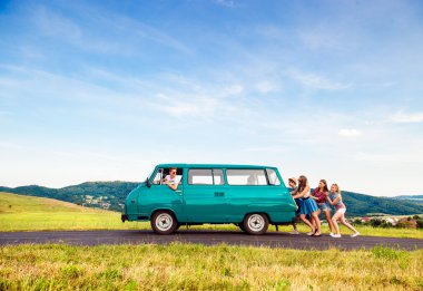 Jumping frieds with campervan, green nature and blue sky