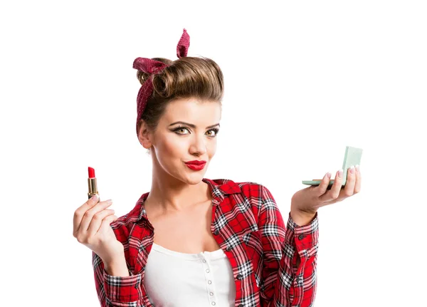 Mujer con pin-up peinado sosteniendo espejo, aplicando rojo lipstic — Foto de Stock