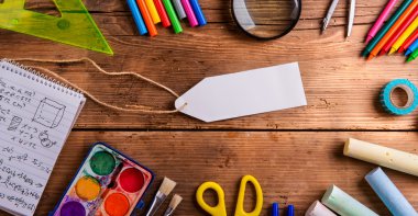 Desk, school supplies, empty tag, wooden background, copy space