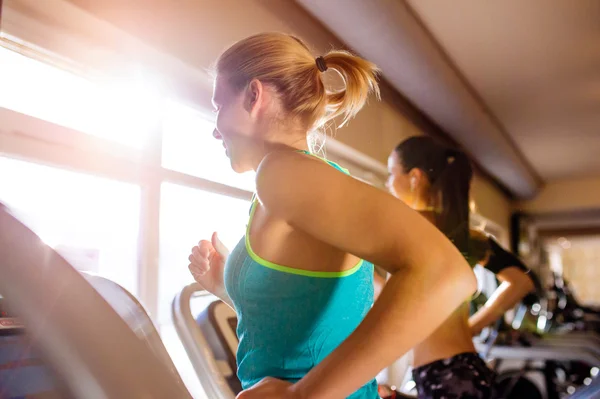 Dos mujeres en forma corriendo en cintas de correr en el gimnasio moderno — Foto de Stock