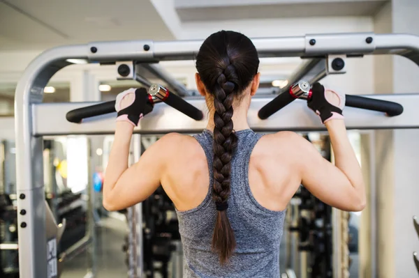 Mulher no ginásio flexionando os músculos das costas na máquina de cabo — Fotografia de Stock