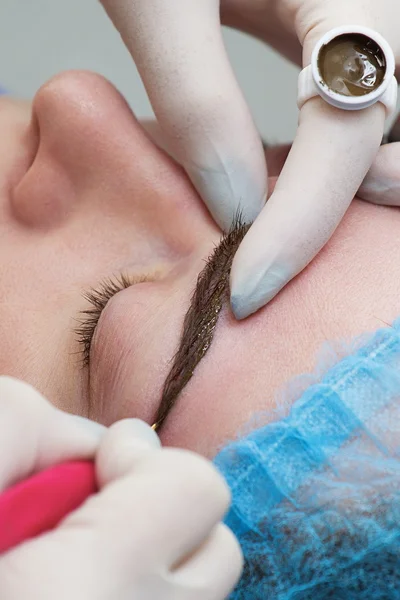 Cosmetólogo aplicando maquillaje permanente (tatuaje) en las cejas . —  Fotos de Stock