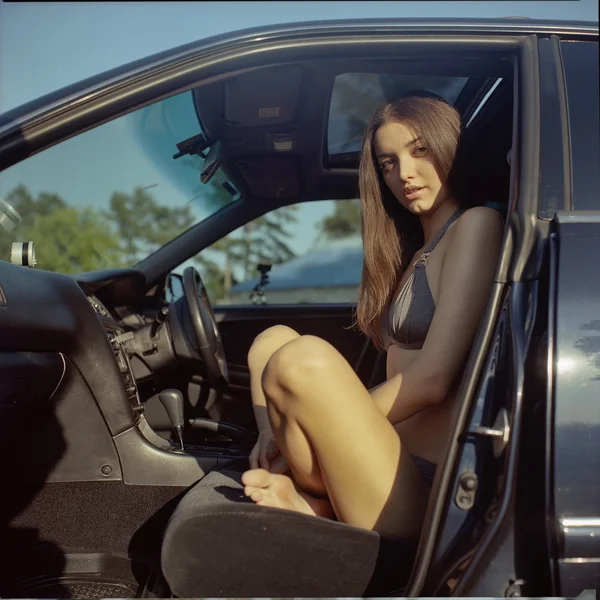 Mujer atractiva sentada en un coche con la puerta abierta . — Foto de Stock