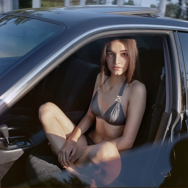 Aantrekkelijke vrouw zitten in een auto met de deur open. — Stockfoto