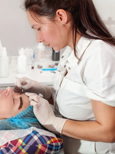 Cosmetólogo aplicando maquillaje permanente (tatuaje) en las cejas . —  Fotos de Stock