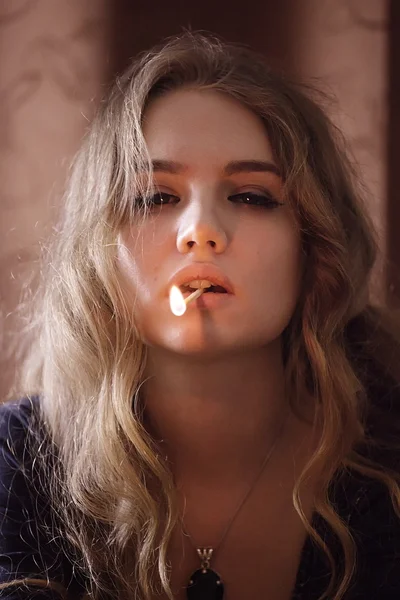 Portrait of young woman with lit match in mouth — Stock Photo, Image