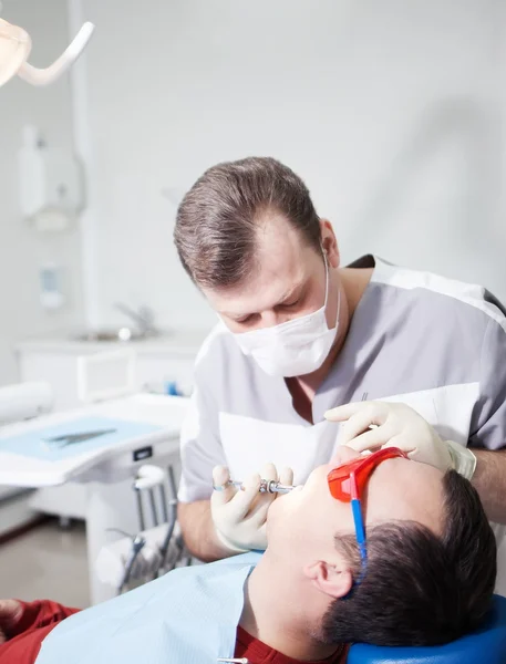 Le dentiste fait un traitement dentaire au patient . — Photo