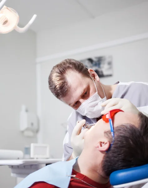 Dentysta sprawia, że leczenie stomatologiczne pacjenta. — Zdjęcie stockowe