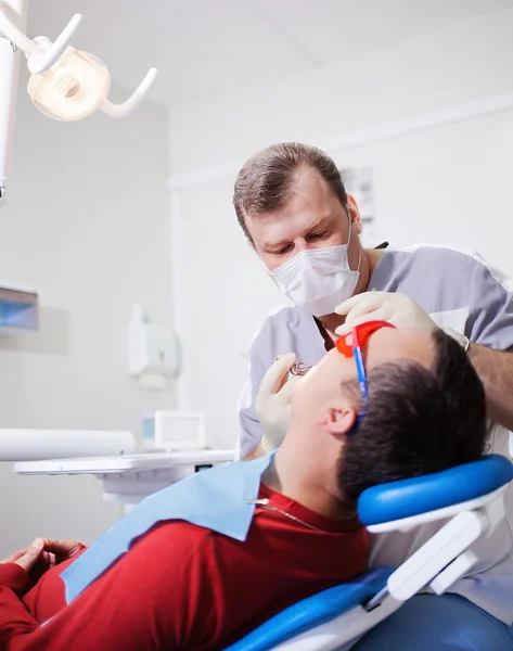 Le dentiste fait un traitement dentaire au patient . — Photo