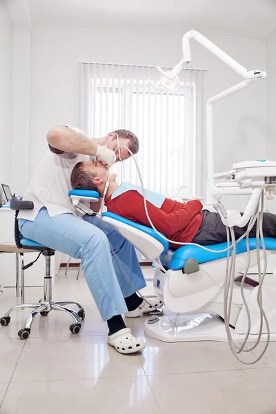 Le dentiste fait un traitement dentaire au patient . — Photo