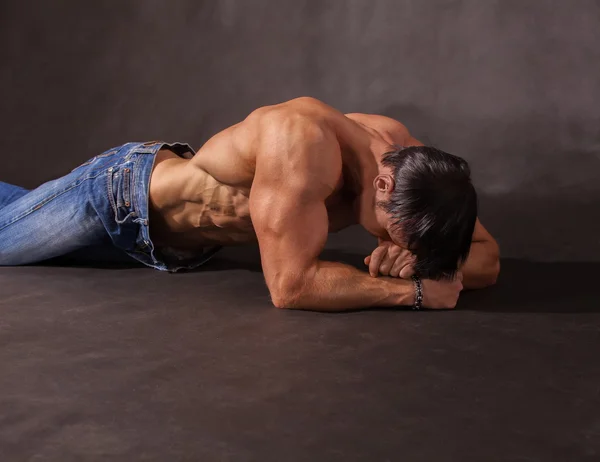 Bodybuilder liggend op de vloer in de studio — Stockfoto