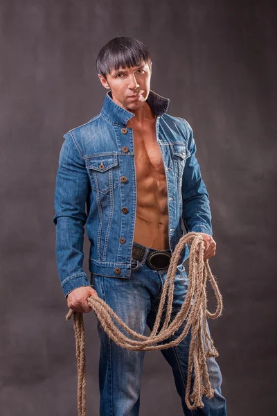 Cowboy i jeansjacka med ett rep. Stockbild