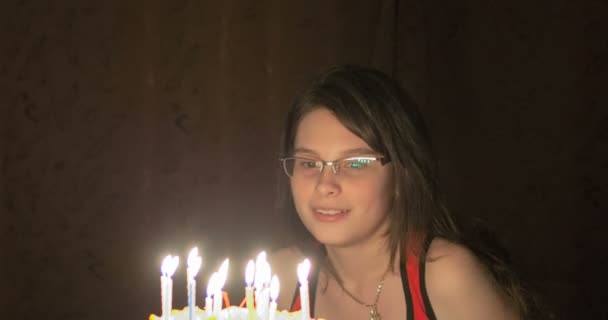 Giovane ragazza seduta davanti a una torta con candele . — Video Stock