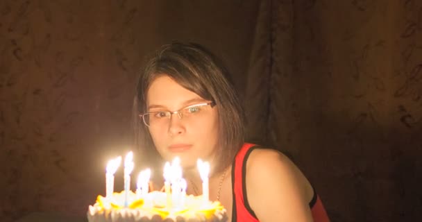 Chica joven sentada frente a un pastel con velas . — Vídeos de Stock