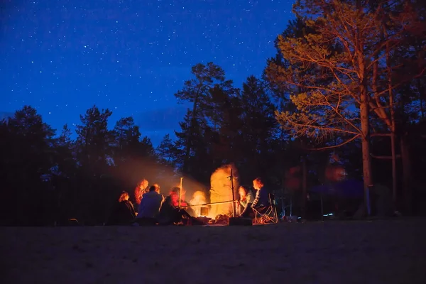 Touristen am Lagerfeuer bei Nacht. Stockbild