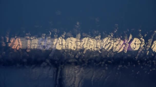 Noche borrosa abstracto de agua corriendo por el vidrio y las luces en el fondo — Vídeo de stock