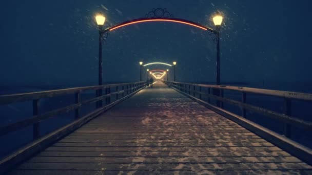 Couple marchant la nuit sur une jetée en bois la nuit pendant une tempête de neige — Video