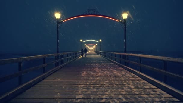 Geceleri kar fırtınası sırasında tahta iskelede yürüyen bir çift. — Stok video