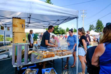 21 Ağustos 2021 - Qualicum Beach, Kanada: Yerel çiftçi pazarındaki Bodhis Esnaf Fırını 'ndan alışveriş yapmak için sırada bekleyen müşteriler