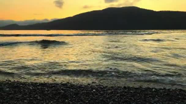 Golven die de kust raken op grindspuug bij zonsondergang in Port San Juan, Port Renfrew, British Columbia, Canada — Stockvideo