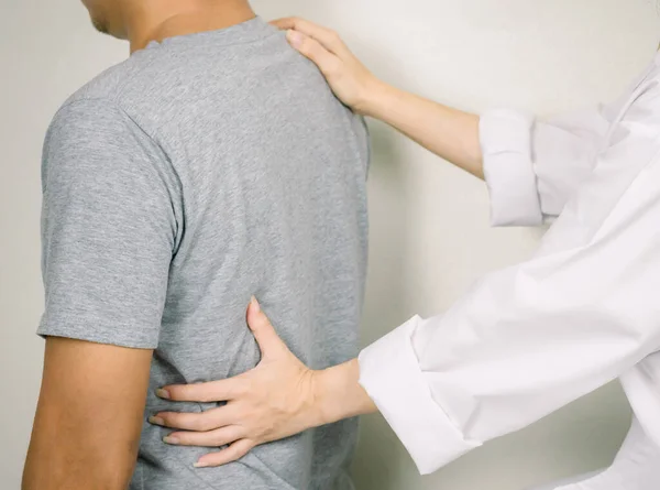 The doctor examines a patient with back pain Inflammation of the back