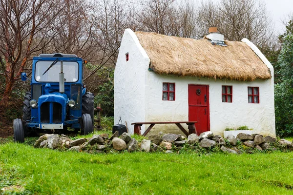 Szalma fedett házikó, és a traktor — Stock Fotó
