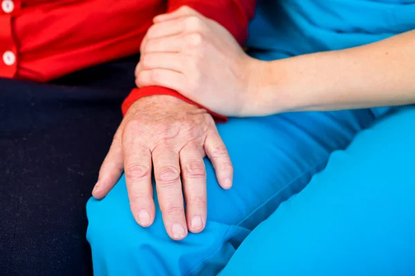 Junge Pflegerin gibt älteren Frauen helfende Hände — Stockfoto