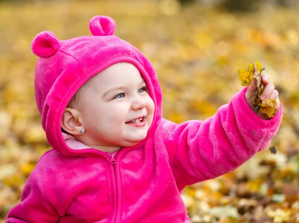 Cute baby girl sitting in autumn leaves