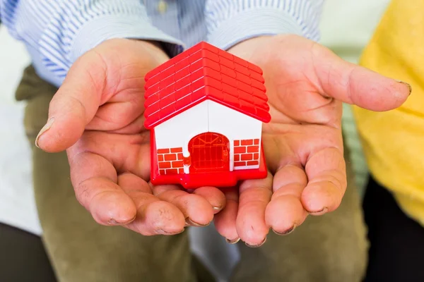 Foto de uma casa em miniatura segurando as mãos — Fotografia de Stock