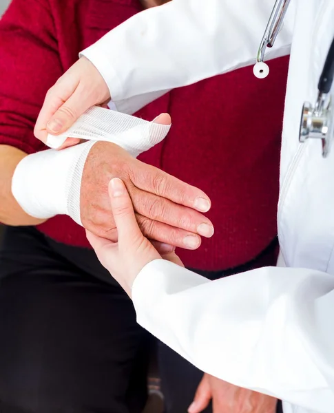 Photo of doctor bandaging the elderly woman thumb — Stock Photo, Image