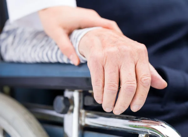 Mains d'une femme âgée reposant sur le fauteuil roulant — Photo