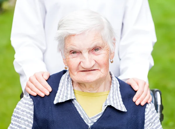 Foto van een jonge verzorger die de oudere vrouw helpt — Stockfoto