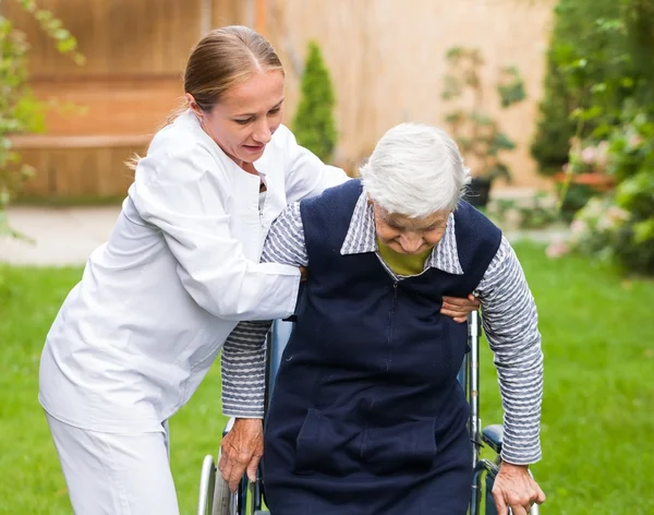 Foto van een jonge verzorger die de oudere vrouw helpt — Stockfoto