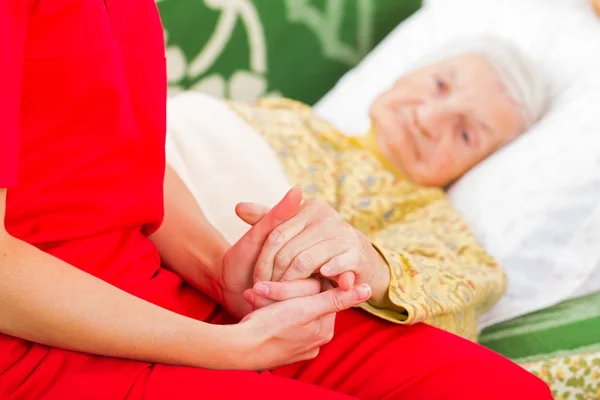 Jovem cuidador dando as mãos de ajuda para a mulher idosa — Fotografia de Stock